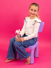 Load image into Gallery viewer, Young girl sitting on a small purple chair against a pink background