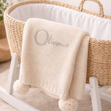 Load image into Gallery viewer, Beige baby blanket with 'Olivia' embroidery on a white stand with a wicker basket in the background.