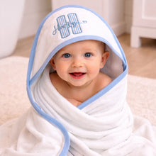 Load image into Gallery viewer, Baby wrapped in a white towel with blue trim, smiling, on a light-colored floor.