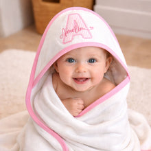 Load image into Gallery viewer, Baby wrapped in a white hooded towel with pink trim, smiling at the camera.