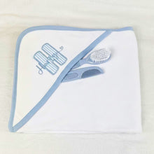 Load image into Gallery viewer, White hooded towel with blue trim and baby care items on a beige background