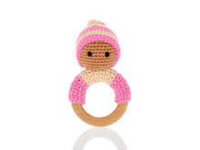 Load image into Gallery viewer, Pink wooden &amp; crochet teething ring rattles. The wood ring is half wrapped with crocheted cotton, a cute head sits on top of the wooden ring with stitched black eyes and a matching bobby hat